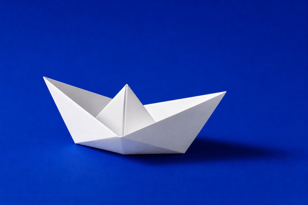Folded white paper boat on a vivid Klein-blue backdrop