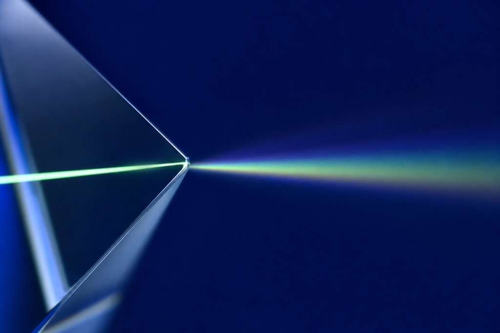 Glass prism refracting a beam of aurora-green light on an ultramarine backdrop